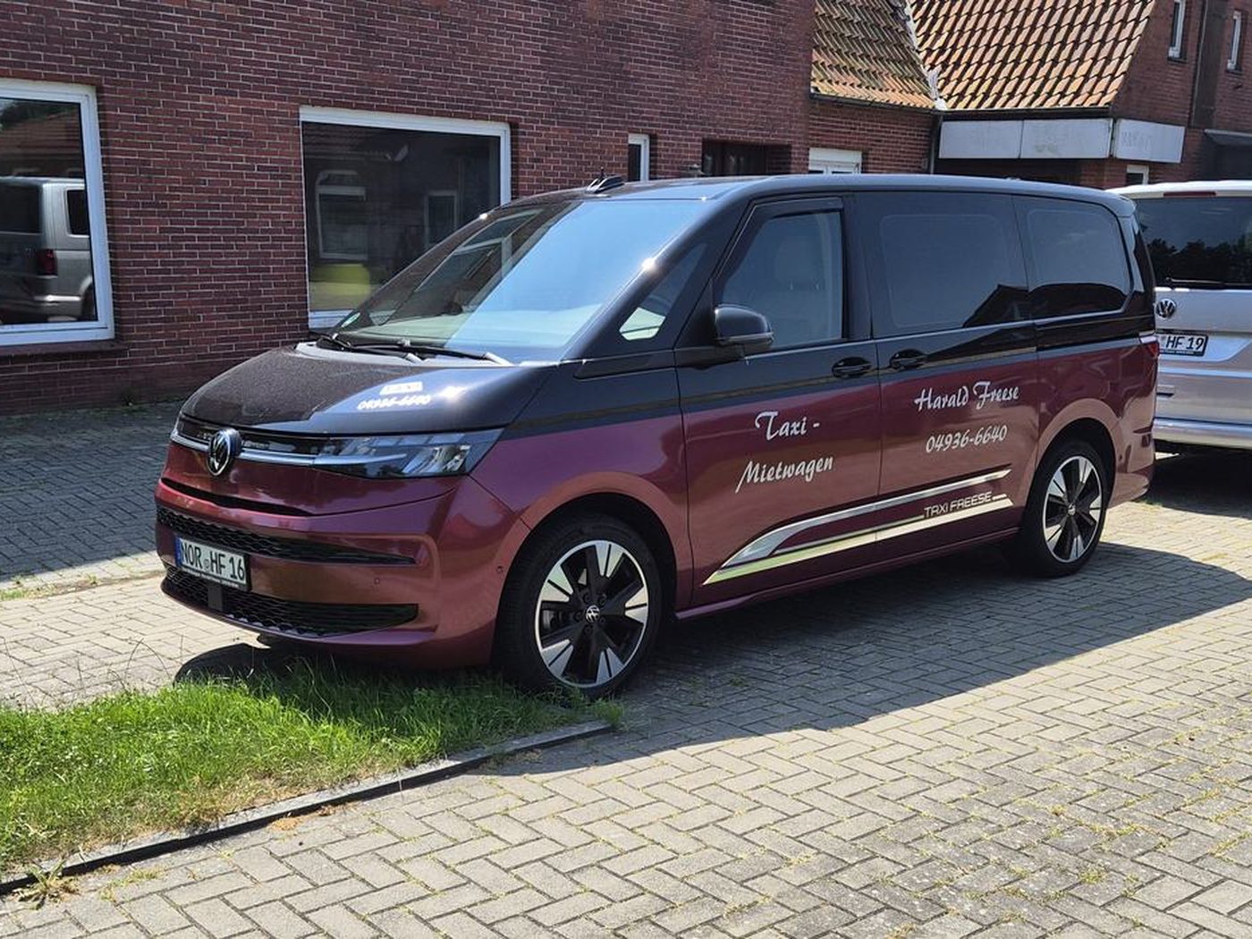 Roter VW Multivan und weißer Bus von Taxi Freese vor dem Firmensitz in Großheide